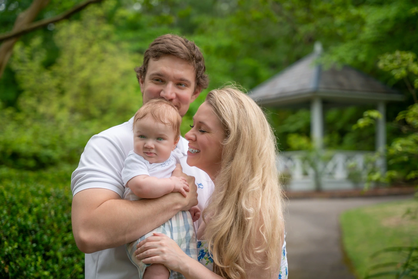 Couple holding their baby in a green garden